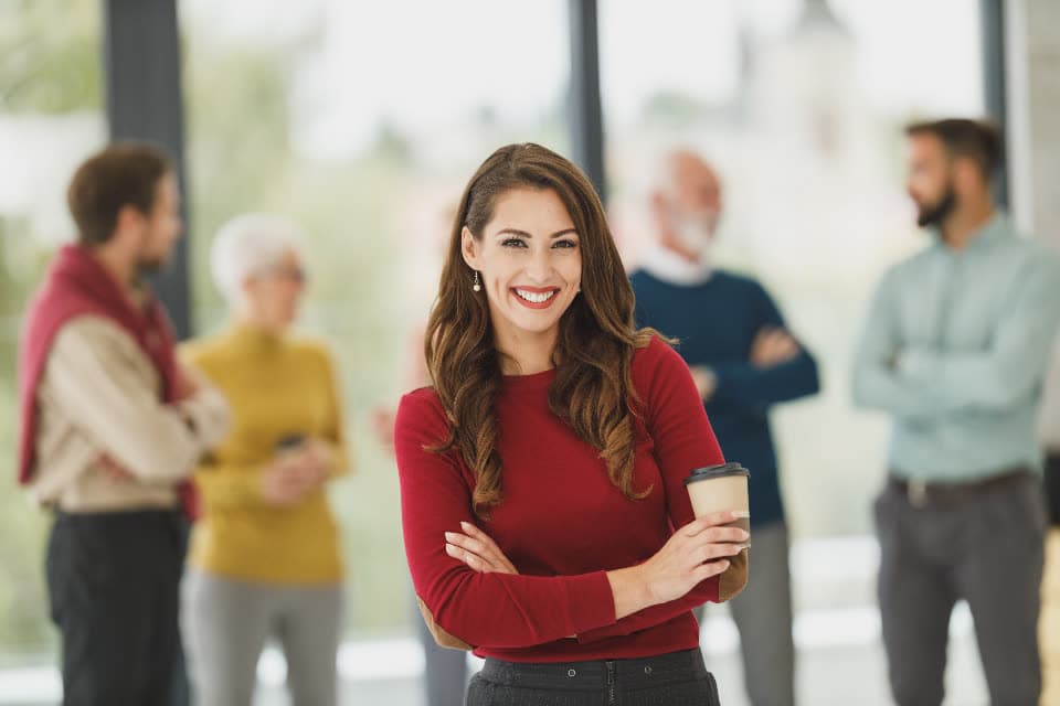 Dona de negócio sorrindo com a equipe ao fundo